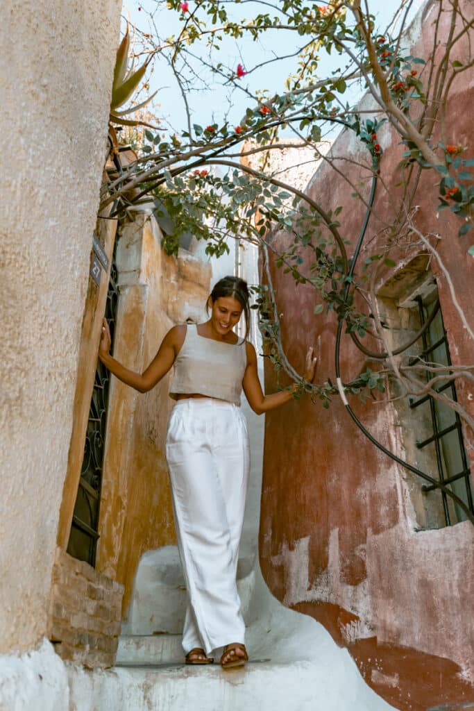 Me standing in a narrow whitewashed alley in Anafiotika with views of Athens in the background.