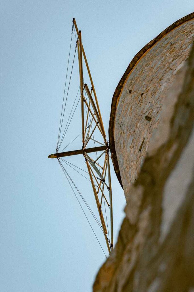Stone windmill with wooden sails against a clear blue sky on Hydra island, a landmark.