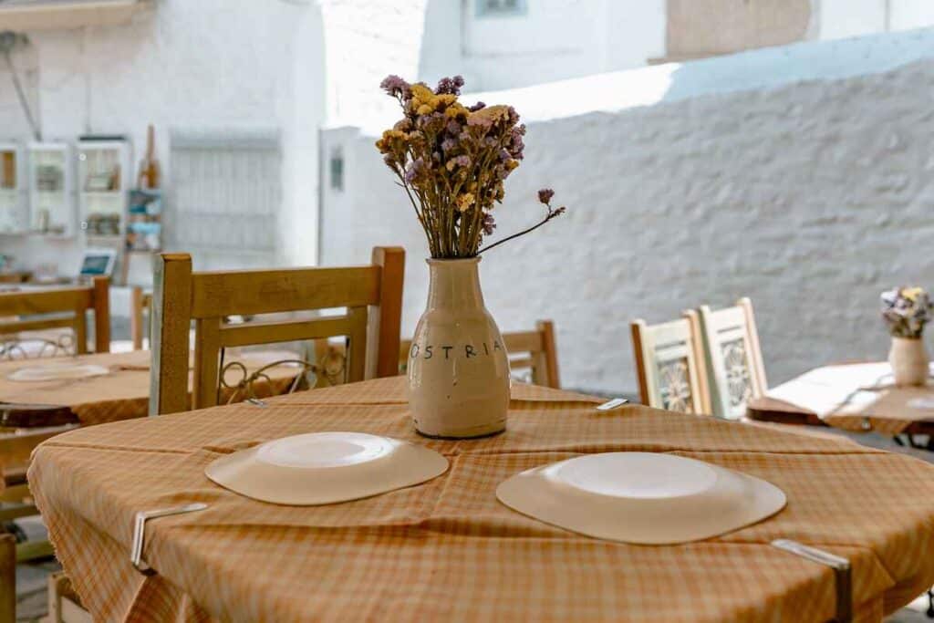 Table set with plates and a vase of dried flowers at a traditional taverna in Hydra.