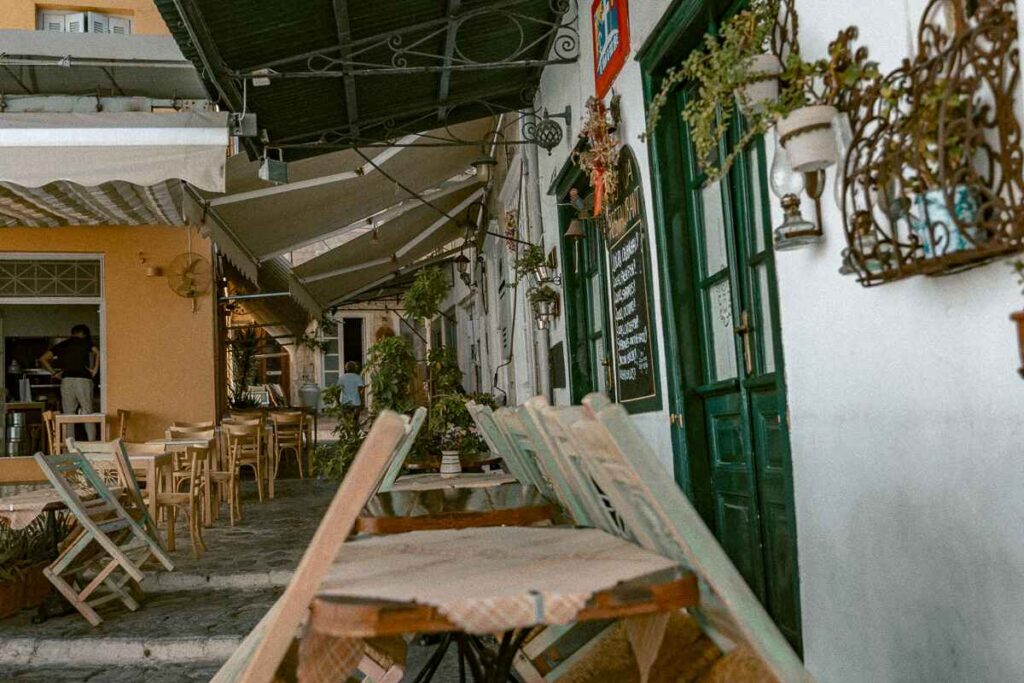 Cozy alley in Hydra with cafés, plants, and colorful doors, a hidden gem to explore.