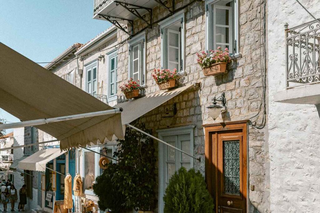 Potted plants on a stone home windowsill. Sunny pathway in Hydra.