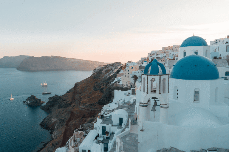 Blue domed church overlooking the Aegean Sea in Santorini, Greece, a dreamy Greek island view perfect for Greece Instagram captions.