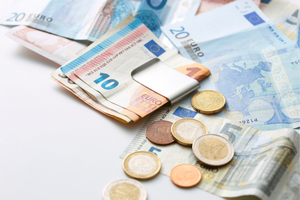 Euro banknotes and coins spread across a white surface, representing travel costs for visitors wondering if Athens is expensive.