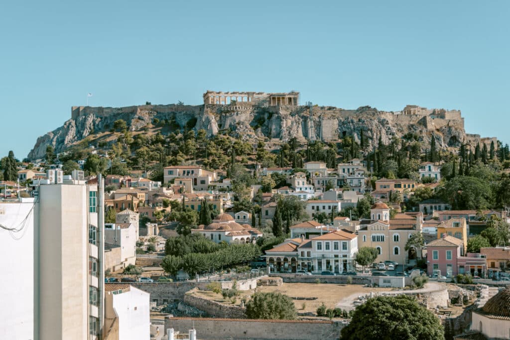 Panoramic view of the Acropolis rising above Athens, with terracotta-roofed houses in Plaka below. A reminder of the city’s mix of history and daily life when considering the cost of visiting Athens.