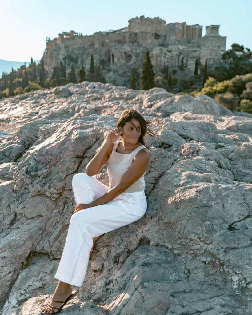 Me sitting on rocky outcrops at Filopappou Hill, looking toward the Acropolis at sunset. Highlights one of Athens’ free experiences with priceless views.