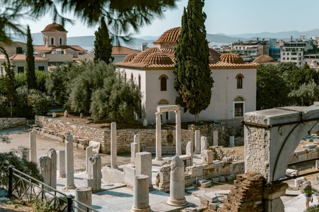 Ruins of the Roman Agora with ancient columns and a domed Byzantine church in the background, reflecting the cost balance of paid sites and free views in Athens. A must see if you're wondering is Athens worth visiting.