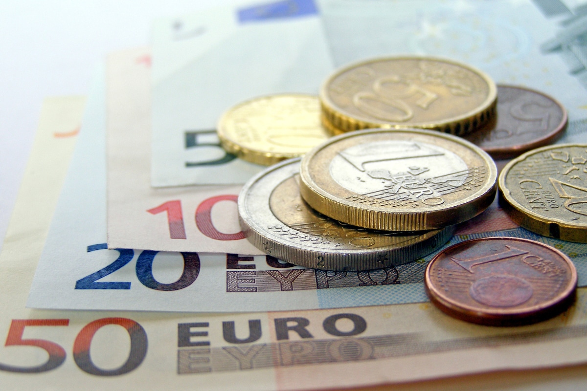 Close-up of euro banknotes and coins, including €50, €20, and €10 bills with one- and two-euro coins stacked on top. This image represents the everyday expenses travelers should budget for when asking is Athens is expensive to visit.