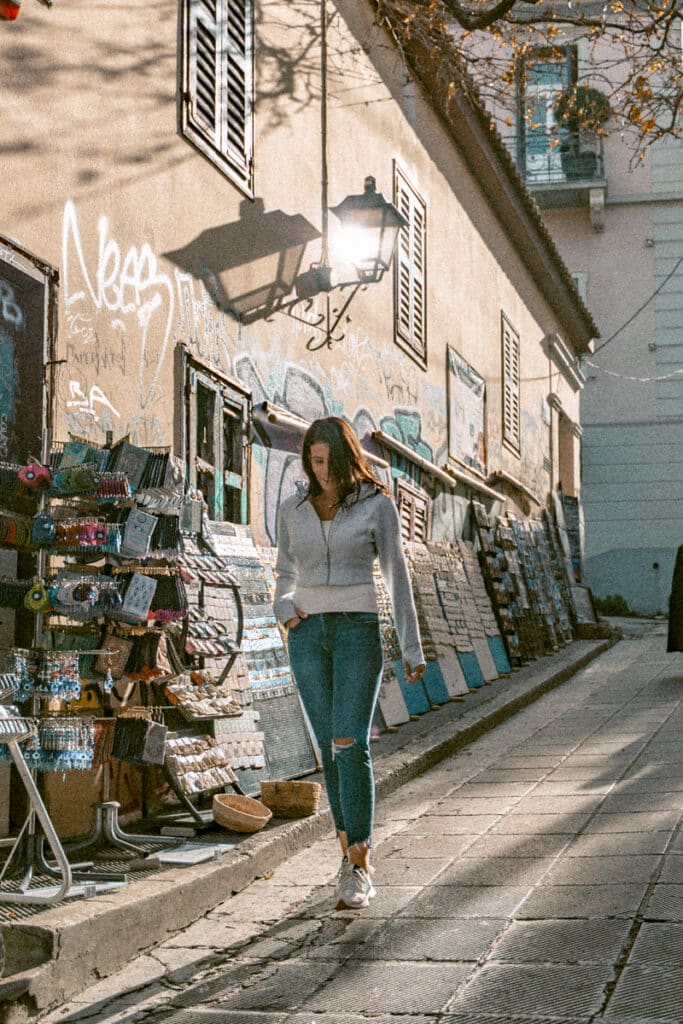 Me walking past market stalls selling souvenirs and jewelry in Athens, with graffiti-covered walls in the background to show the answer to the question is Athens safe.