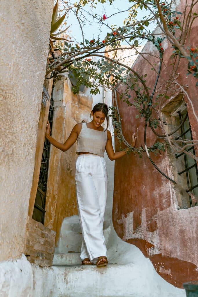 Me walking through a narrow, colorful alley beneath flowering vines in Anafiotika, Athens.