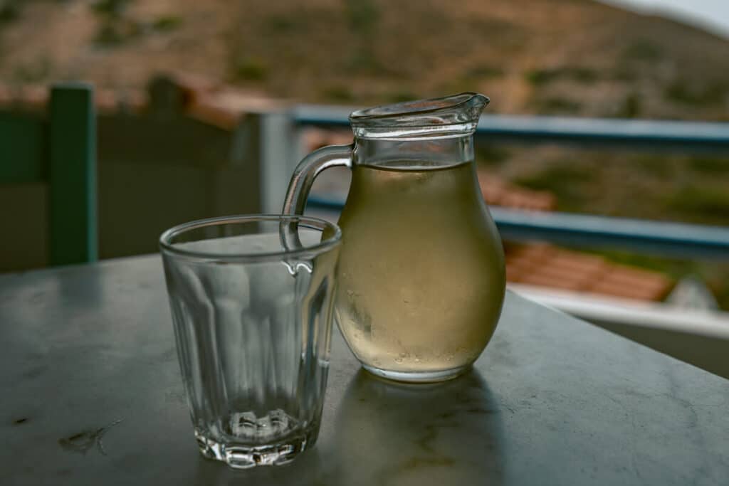 Pitcher of wine and wine glass filled on a table at a cafe in Ikaria.