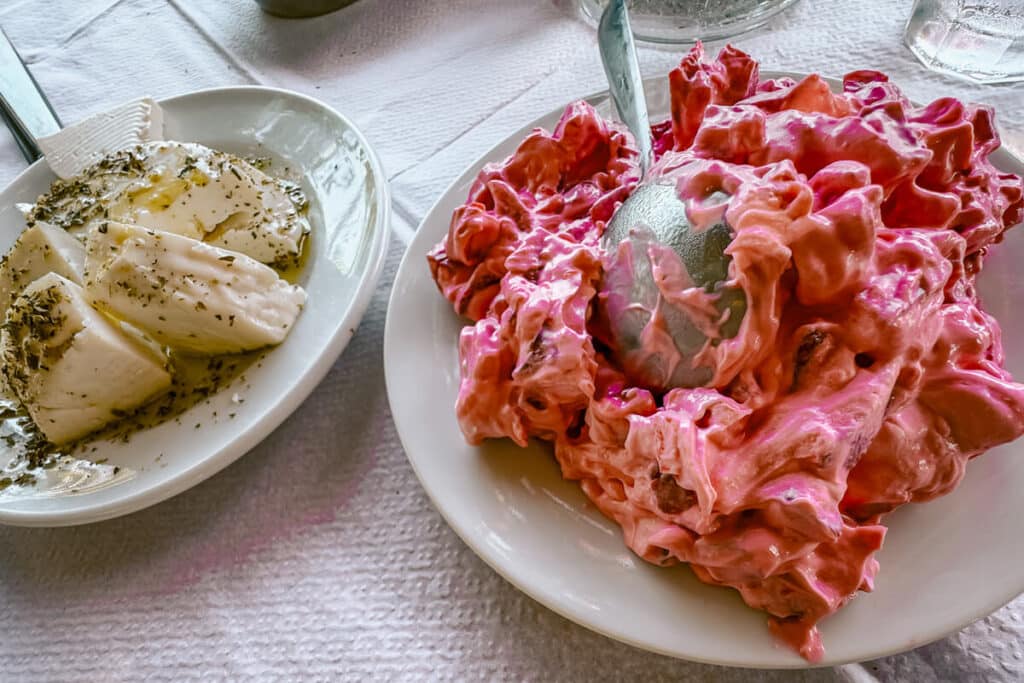 Greek meze on a table in Ikaria—fresh local cheese drizzled with olive oil and herbs beside a vibrant beet salad, showcasing the flavors of Ikaria, Greece.