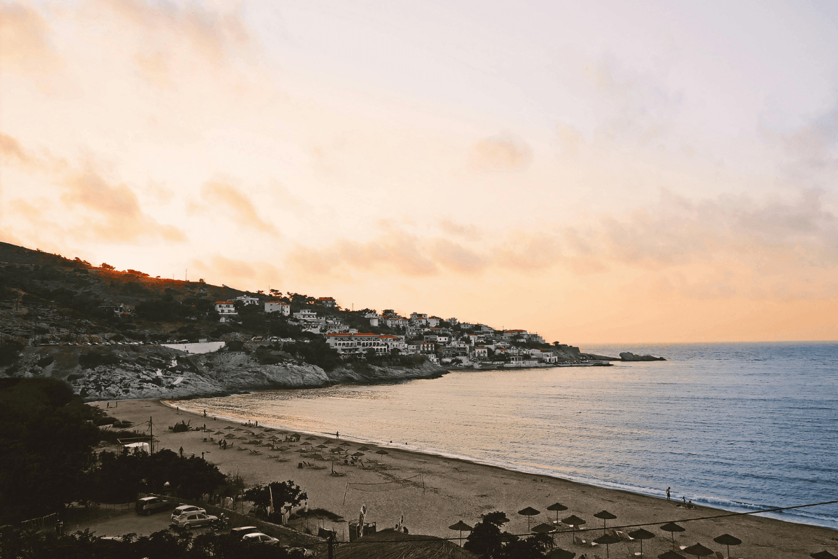 Ikaria beach and coastal village at sunset, highlighting the island’s mountainous seaside scenery in this Ikaria travel guide.
