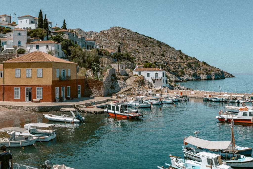 Small fishing boats docked in a charming harbor with pastel houses built into the hillside.