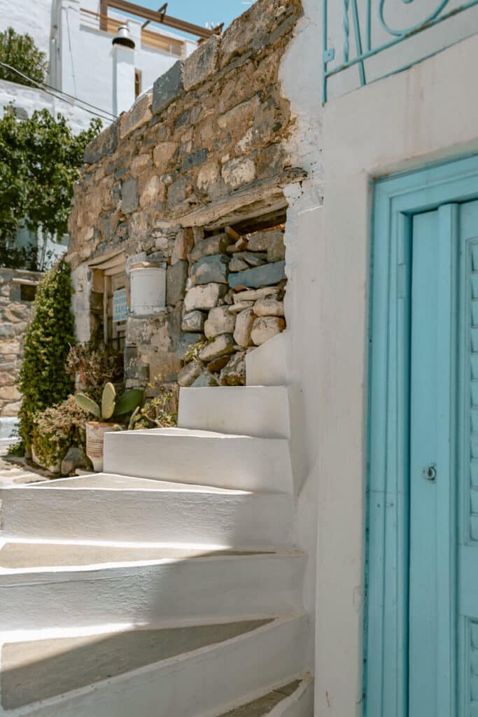 Rustic stone wall and curved white staircase in Serifos, blending old Cycladic architecture with bright turquoise accents.
