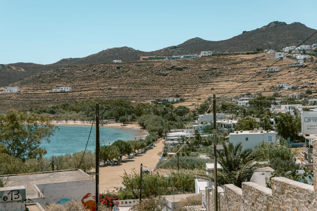 View overlooking Livadi Beach in Serifos with golden sand, turquoise water, and tamarisk trees lining the shore.