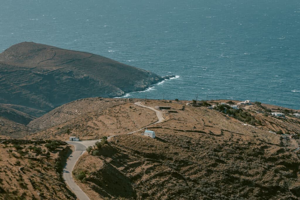 View from the winery in Serifos showing a winding coastal road through Serifos hills with views of rocky cliffs and the shimmering sea below.