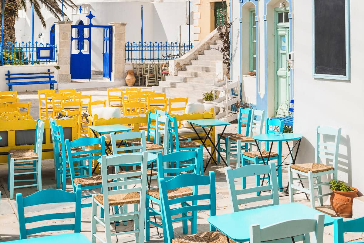 Chora in Serifos filled with colorful turquoise and yellow chairs under the bright Greek sunlight, creating a lively summer scene and one of the top things to do in Serifos is visiting the Chora.