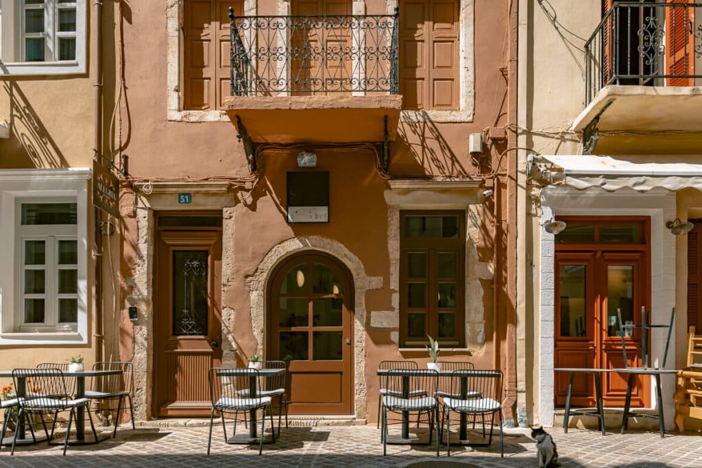 Cafe tables outside colorful buildings in Chania Old Town, Greece.