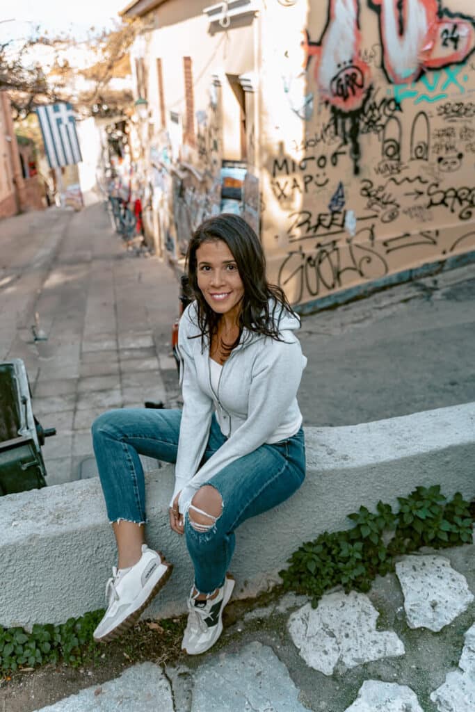 Me sitting relaxed on a stone ledge in Plaka, Athens surrounded by street art, capturing the vibrant and safe vibe.