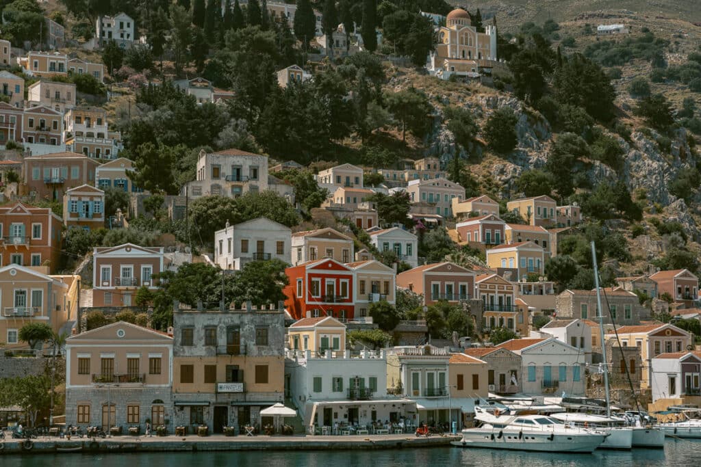 Colorful hillside houses and boats in the harbor on Symi island, Greece.