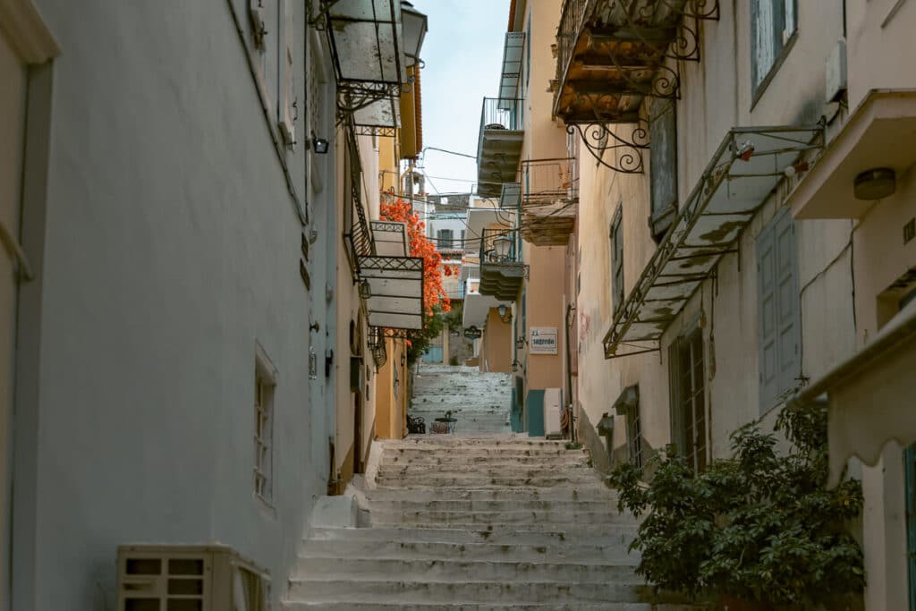 Peaceful alley with whitewashed steps and blooming flowers in Nafplio, Greece.