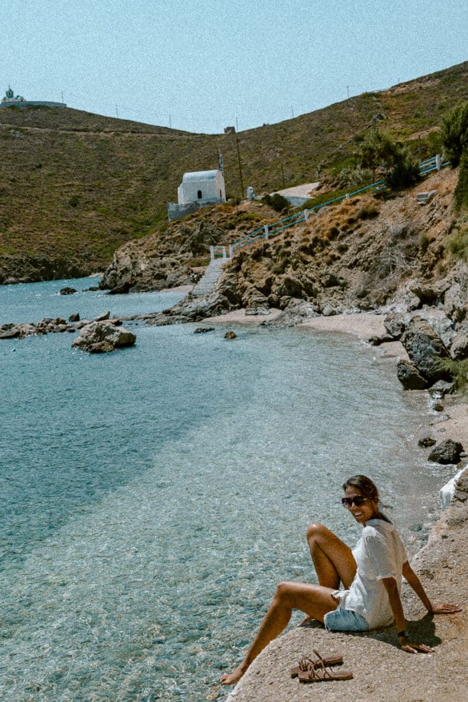 Me enjoying solitude by the sea with a white chapel in the background on a remote beach in Thymaina.