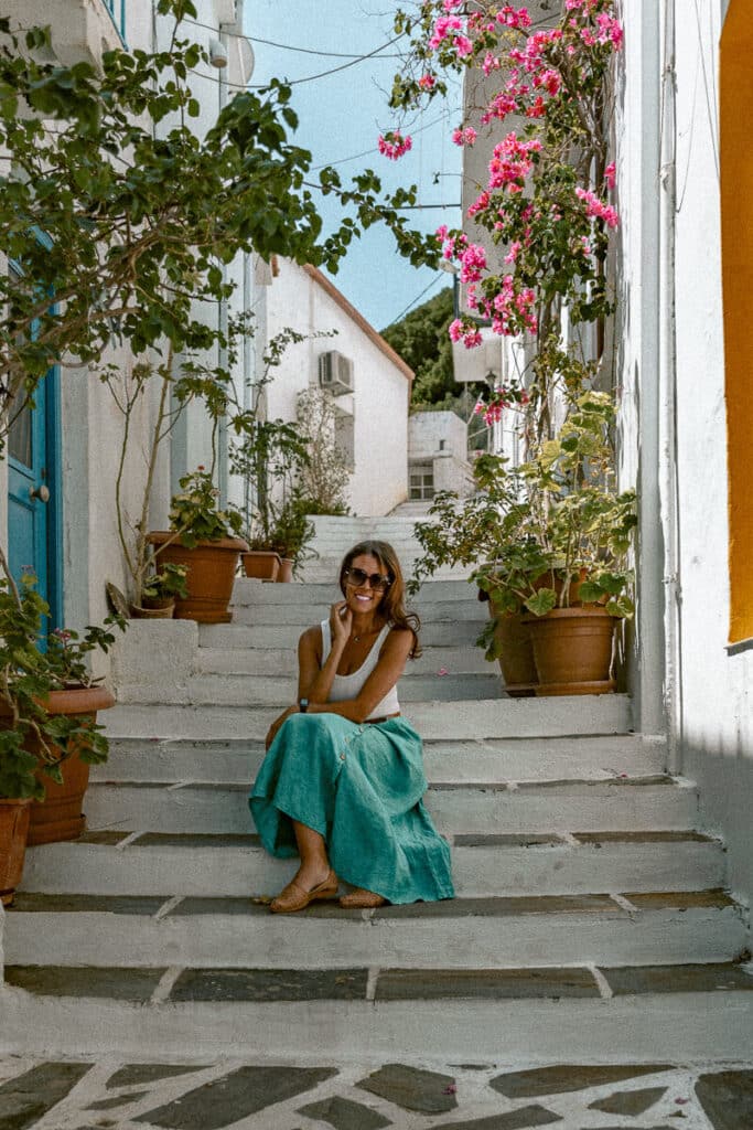 Me sitting on charming village steps surrounded by flowers, symbolizing ease and safety during female solo travel in Greece.