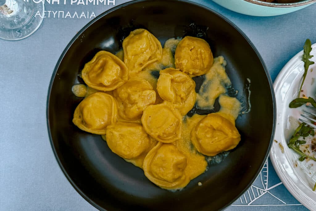 Saffron pasta filled with Astypalaia cheese served in a black bowl at Άγονη Γραμμή in Astypalaia.