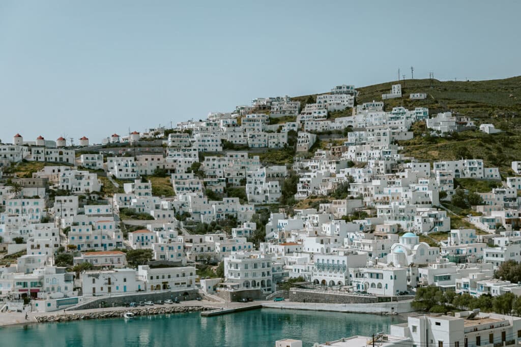 Rows of whitewashed houses with blue shutters stacked on the hillside of Chora, Astypalaia, spilling down to the port