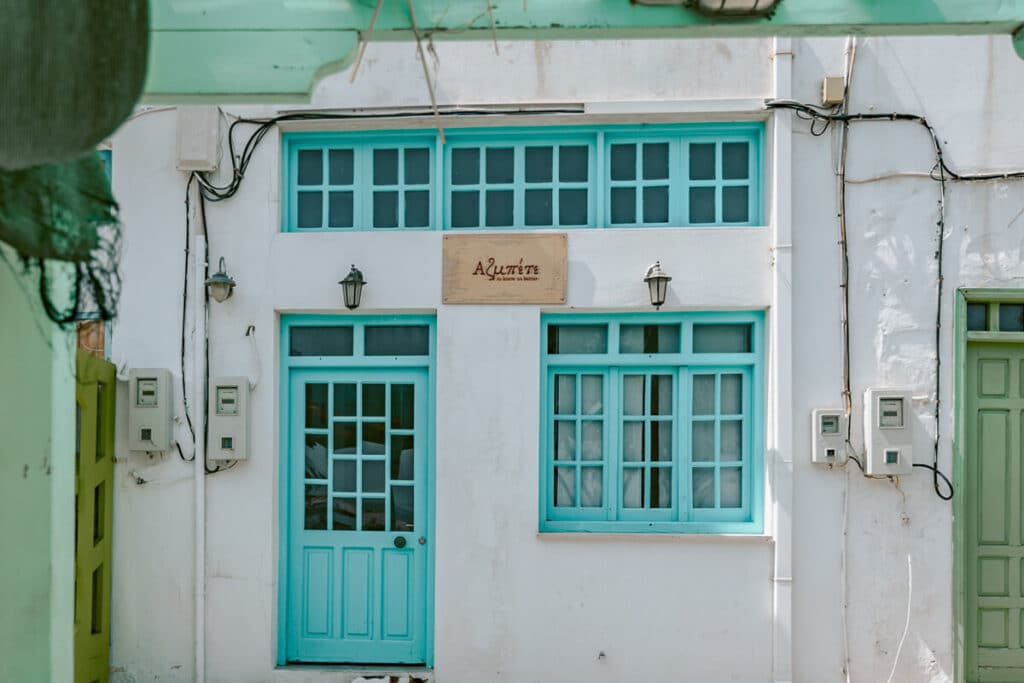 A charming white building with turquoise window frames and doors in Astypalaia’s Chora