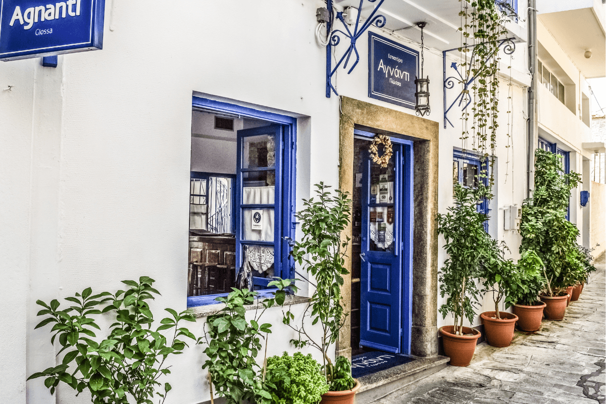 Traditional Greek taverna with blue doors and potted plants, a charming stop to include in a 1 week in Greece itinerary.