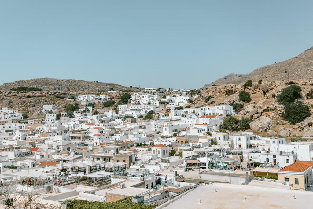 View over the whitewashed village of Lindos in Rhodes, with hillside homes and rocky landscapes that make this a scenic stop on a 1 week in Greece itinerary.