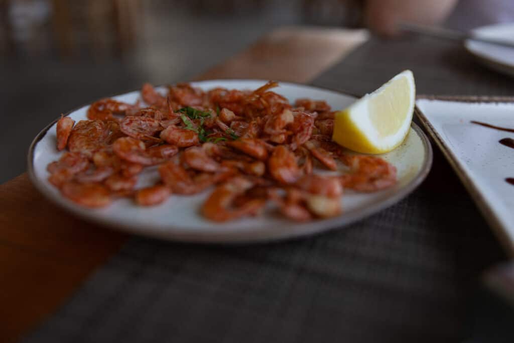 Plate of Symi shrimp with a lemon wedge, a local seafood dish to try during a day trip to Symi from Rhodes.