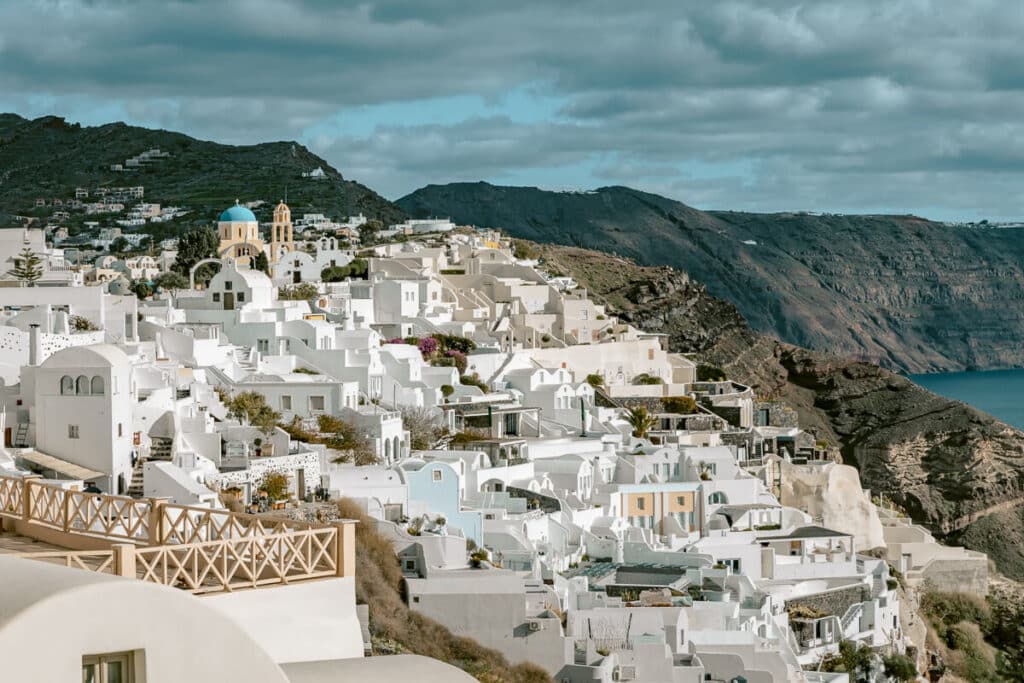 The whitewashed buildings of Oia spilling down the cliffside, with views of the volcanic caldera and deep blue sea—captured during the peaceful off-season of Santorini in winter.