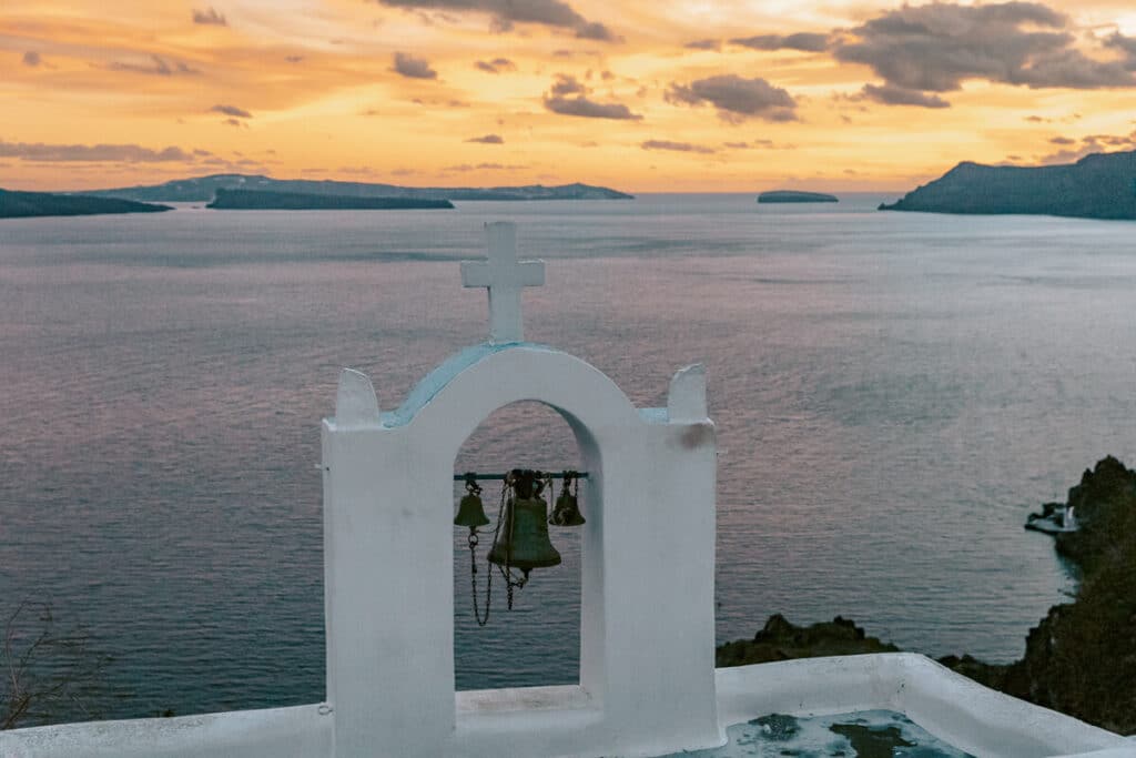 Turquoise door on a white house in Oia overlooking the caldera at sunset