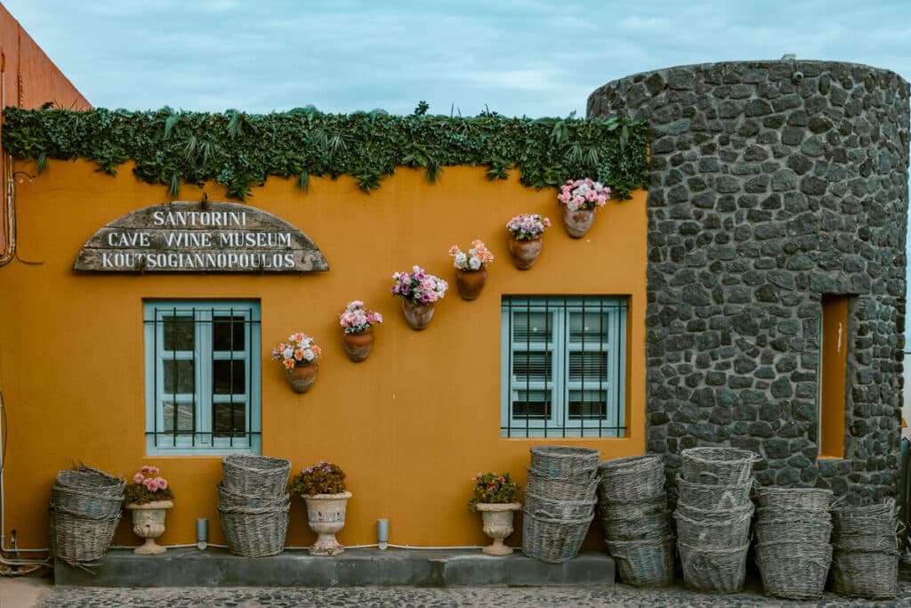 Exterior of Koutsoyannopoulos Wine Museum with yellow wall and flower pots
