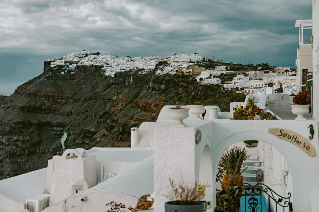View of Santorini caldera with white buildings on cliffside under overcast sky