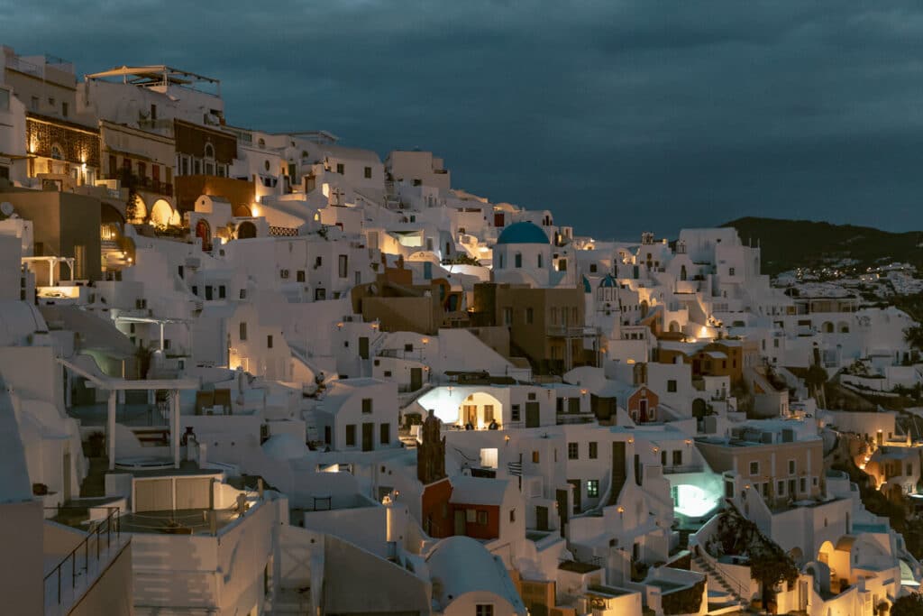 Nightfall over Oia with warm lights glowing from Santorini's whitewashed homes