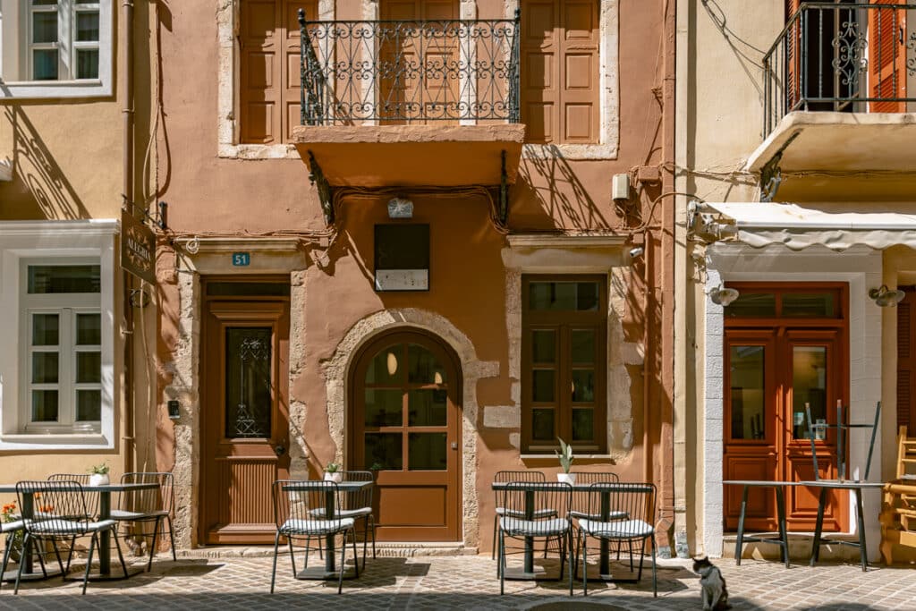 Outdoor cafe tables in front of a pastel building in Chania Old Town, Crete