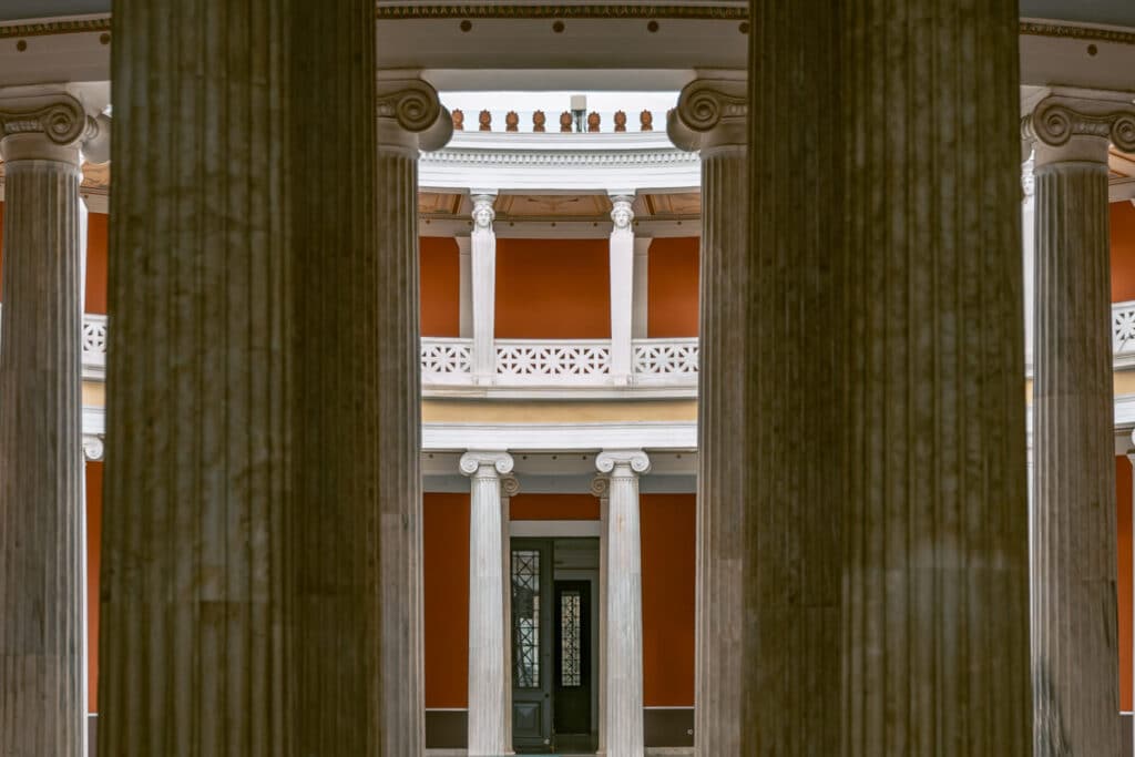 Interior courtyard framed by tall columns and warm colored walls in an Athens museum, emphasizing classical architecture and cultural stops during a city visit.