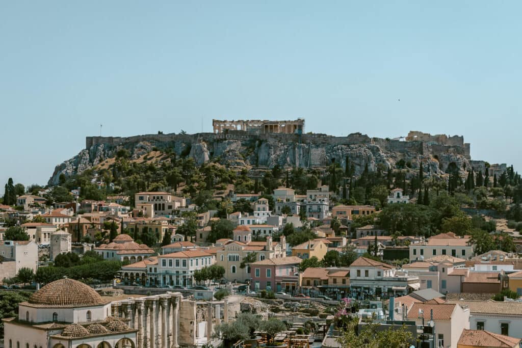 Closer view of the Acropolis perched on a rocky hill above Athens, surrounded by historic buildings and greenery, emphasizing the cultural highlights of a Greece city visit.