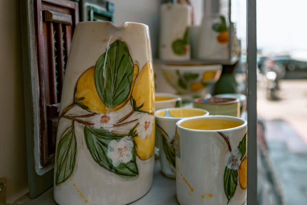 Hand painted ceramic pitcher and cups decorated with lemons and green leaves in a shop window in Aegina.