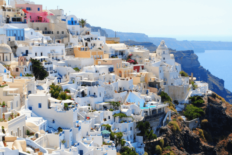 Whitewashed buildings with colorful accents along the dramatic caldera cliffs, a classic Santorini setting to consider when planning what to wear in Santorini.