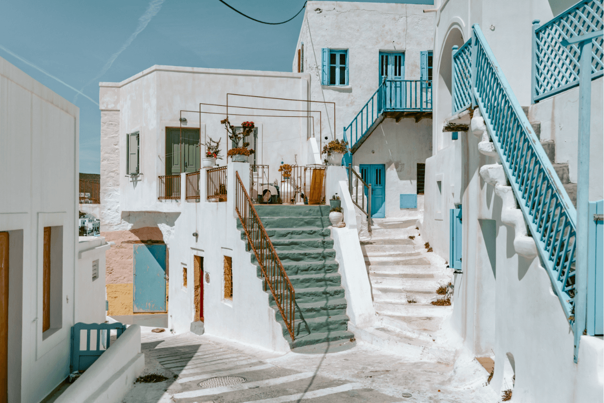 Whitewashed Greek island houses with blue doors, shutters, and staircases, a romantic setting for a honeymoon in Greece.