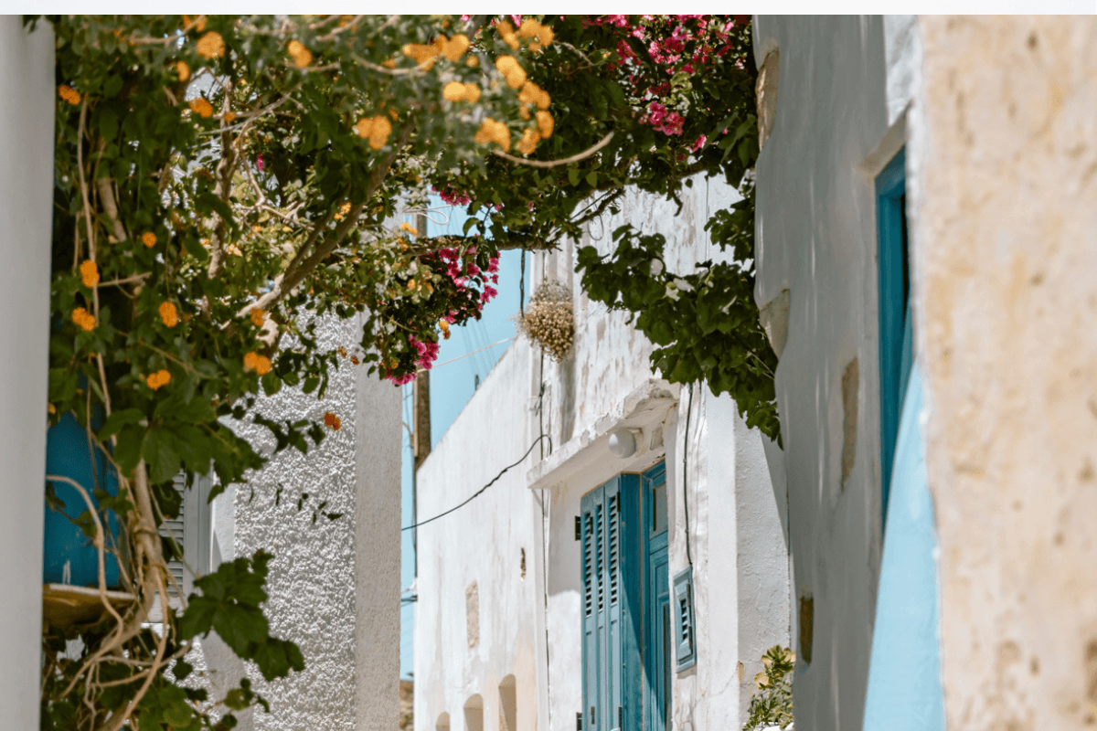 Whitewashed Greek island alley with blue doors and colorful bougainvillea, ideal for planning the best time to visit Greece.