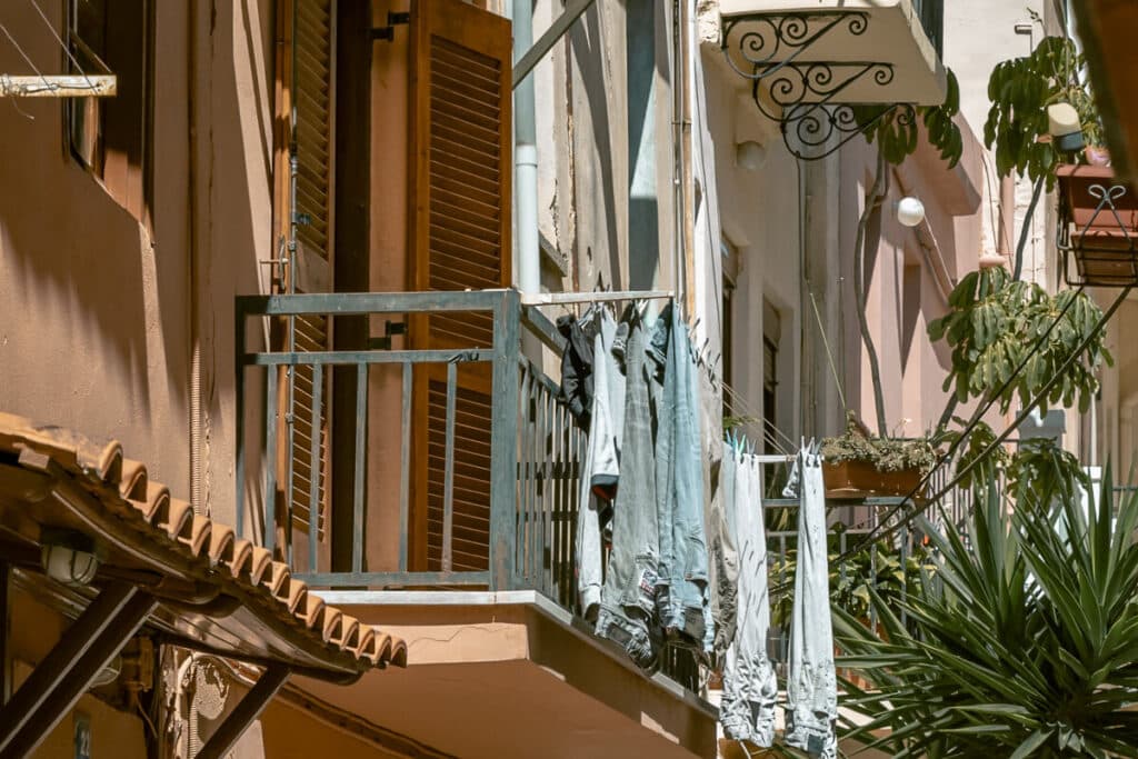 Balcony with hanging laundry between pastel buildings in Chania Old Town, showing everyday life in a narrow street