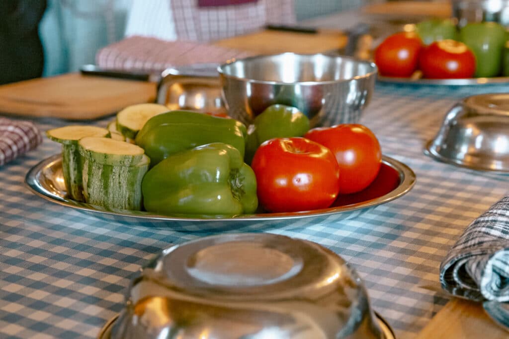 Plate of fresh vegetables set out for a Cretan cooking class near Chania, with peppers, tomatoes, and zucchini on a checkered table