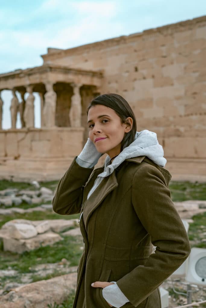 Me wearing a warm coat and hoodie while standing near the Erechtheion at the Acropolis, showing a cold-weather outfit for Athens.