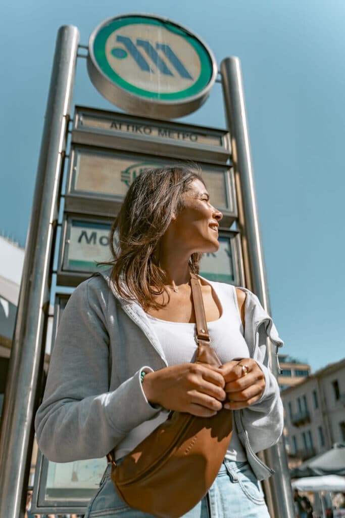 Me wearing a crossbody sling bag while standing near a metro sign in Athens, showing a secure bag option for city sightseeing.