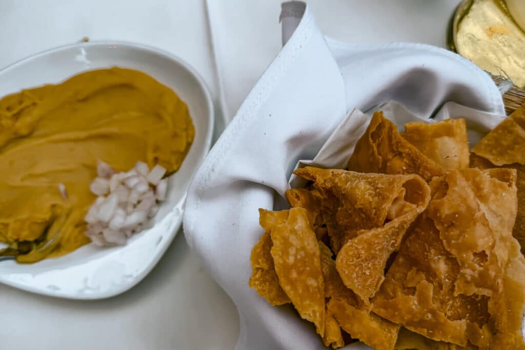Basket of crispy pita chips served beside a creamy fava with chopped onions at a restaurant in Rhodes.